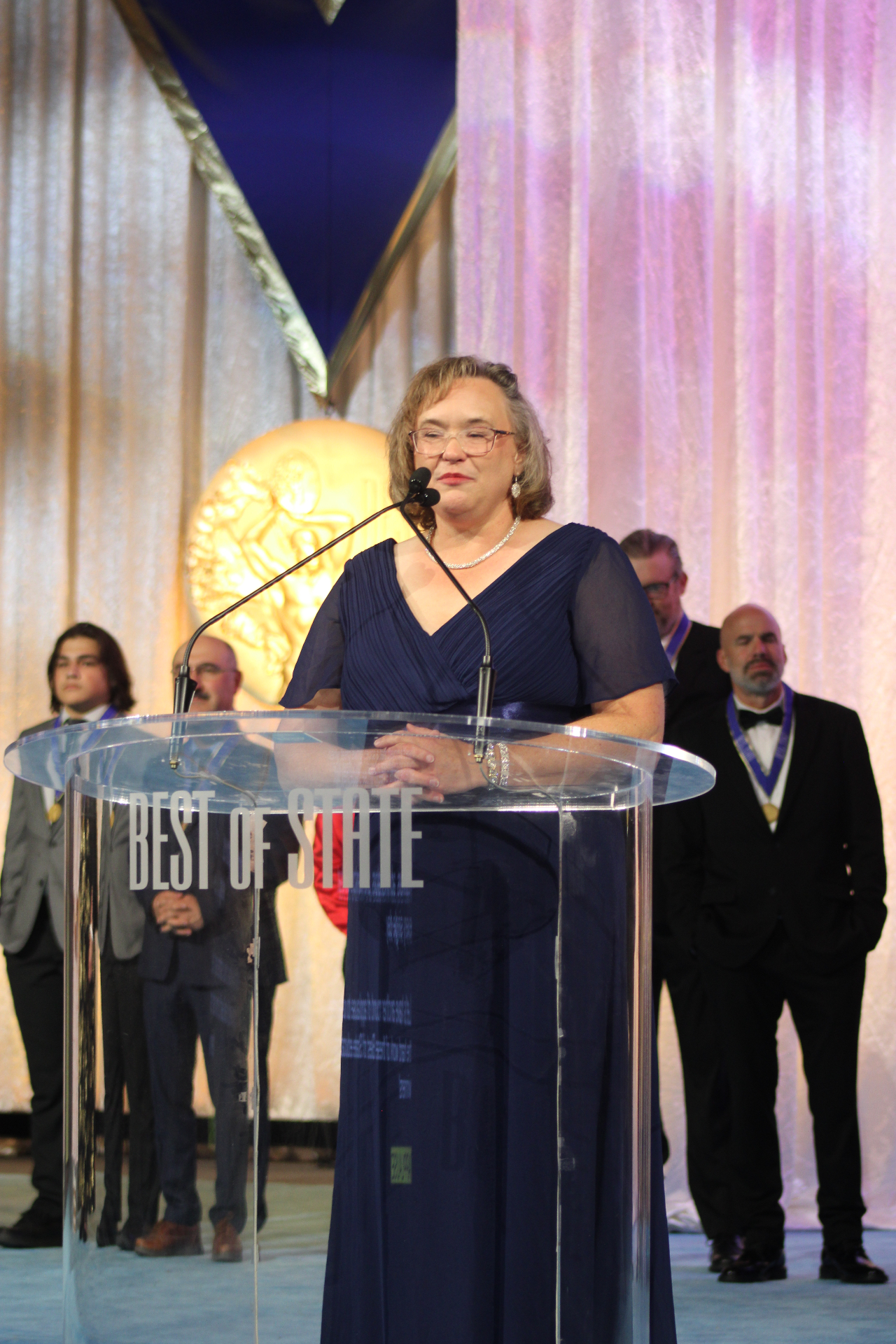 A 2026 honoree addresses the room from the Best of State podium.