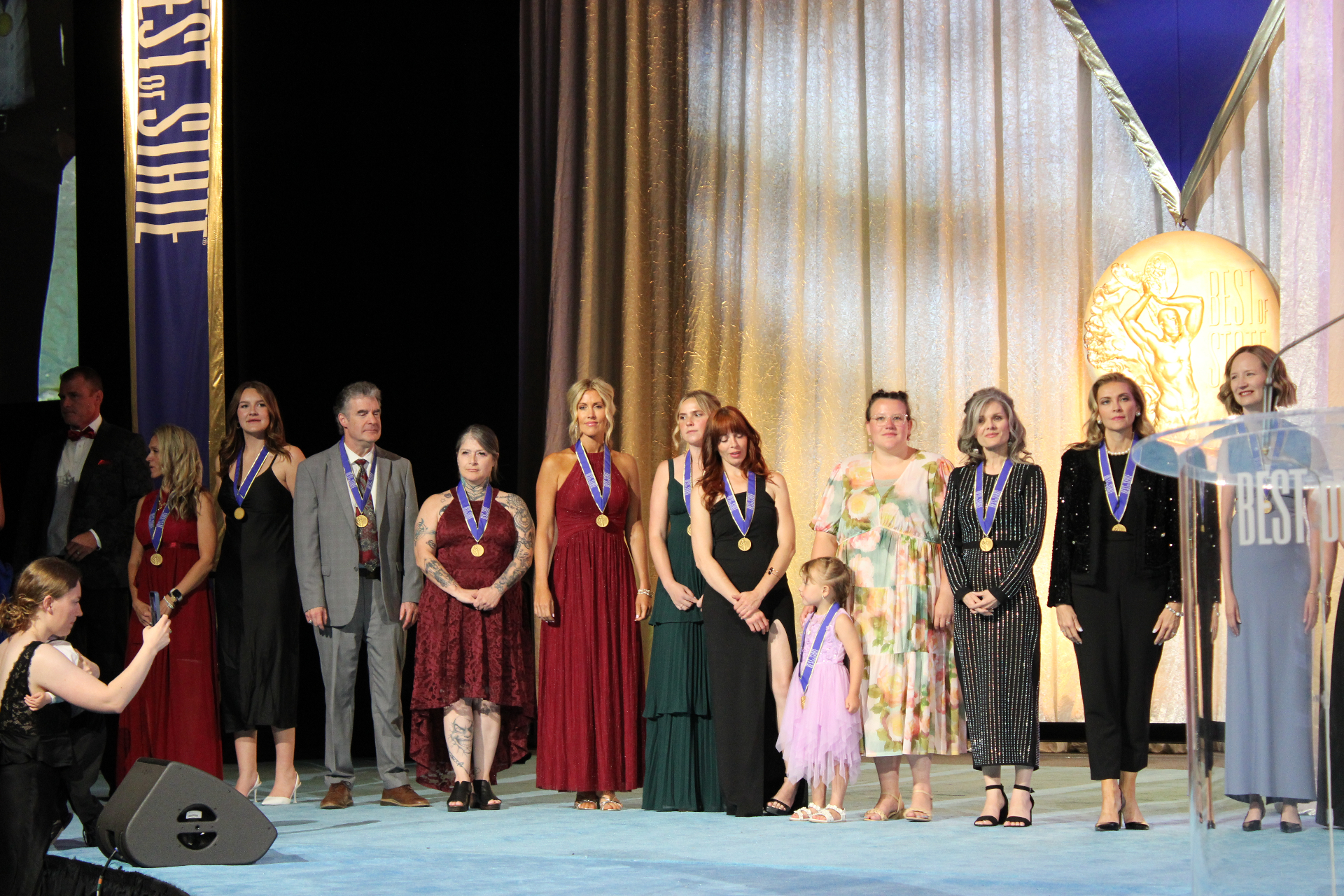 2026 medalists line the stage in formalwear before the BOSS® backdrop.